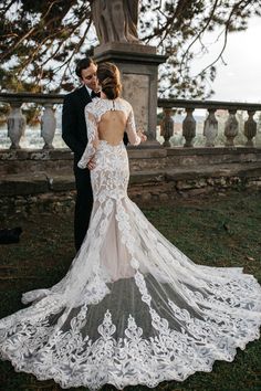 a bride and groom standing in front of a tree with their back to the camera