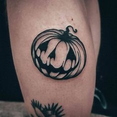 a black and white pumpkin tattoo on the leg