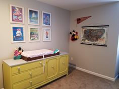 a baby's crib in the corner of a room with pictures on the wall