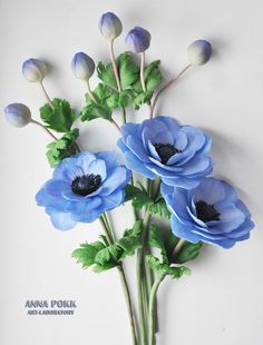 blue flowers are arranged in a vase on the wall