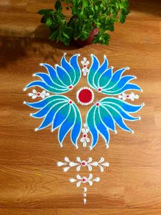 a blue and red design on the floor next to a potted plant with green leaves