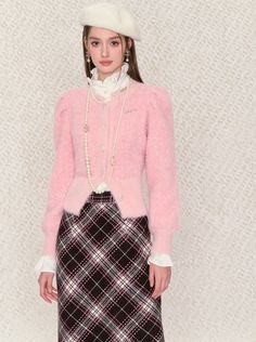 a woman in a pink sweater and plaid skirt with a white hat on her head