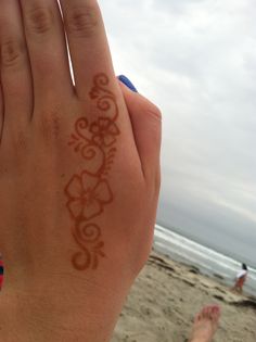 someone is holding their hand up in front of the ocean with an intricate design on it