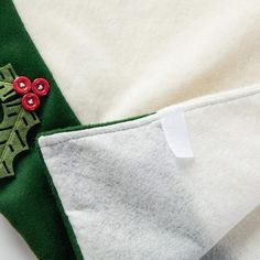 a green and white christmas sweater with holly appliqued on the chest pocket