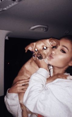 a woman holding a dog in her arms while wearing a white shirt and red tie