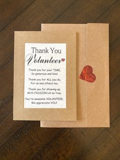 two brown envelopes with red hearts on them and a thank you volunteer note attached