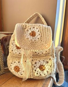 a crocheted bag with flowers on it sitting next to a framed photo and mirror