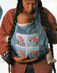 a woman holding a baby wearing a blue bib and braids in her hands