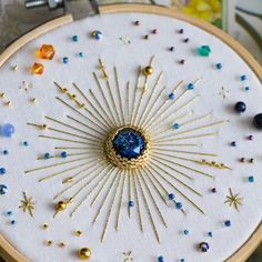 an embroidery project with beads, pins and needles in the shape of a sunburst