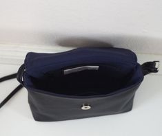 "This small crossbody bag features soft black leather with fabric lining, an adjustable shoulder strap, and a magnetic closure. Details: -Dimensions: 7\" length (top to bottom), 8\" bottom width (side to side), 3\" depth, 8\" X 3\" base (bottom) -Shoulder strap measures approx. 45-50\" total (adjustable) -Navy interior lining -Internal pocket -Magnetic closure Because each bag is made by hand, the measurement is approximate and may vary slightly from one bag to another. Options: #1 Vegan (fake) Black Shoulder Bag With Fold Over Clasp For Business, Black Flap Bag With Fold Over Clasp For Business, Black Leather Satchel With Fold Over Clasp, Black Saddle Bag With Magnetic Closure For Formal Occasions, Black Travel Flap Bag With Fold Over Clasp, Black Formal Saddle Bag With Magnetic Closure, Black Crossbody Saddle Bag With Magnetic Closure, Black Flap Bag With Adjustable Strap, Black Rectangular Flap Bag With Fold Over Clasp