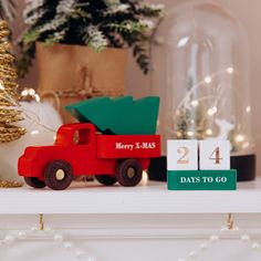 a wooden toy truck with a christmas tree in the back sitting on a mantel