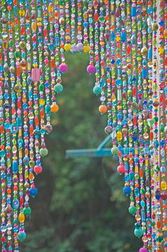 an open door with beads hanging from it's sides and trees in the background