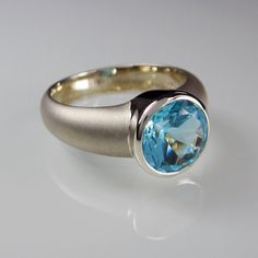 This Artemis Ring is made from brushed Sterling Silver and set with a genuine, natural 10 mm sky blue Topaz. Hallmarked in London UK Topaz Topaz is a silicate mineral of aluminium and fluorine and is found in a variety of colours such as blue, brown, orange, yellow green and fuschia (reddish pink). It's hardness is 8 on the Mohs hardness scale. Sometimes the material is treated in order to enhance the color. The name may be derived from the Sanskrit word "tapas" meaning heat or fire. It is said Modern Blue Topaz Round Ring, Modern Blue Topaz Ring, Round Shape, Modern Round Blue Topaz Ring, Modern Blue Topaz Ring With Tension Setting, Modern Blue Rings With Bezel Setting, Modern Blue Topaz Ring For Wedding, Modern Topaz Anniversary Ring, Modern Blue Topaz Wedding Ring, Modern Blue Topaz Ring