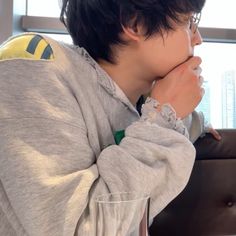 a young man sitting on top of a couch next to a glass filled with liquid