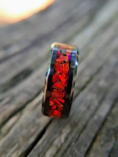 "This beautiful, black ceramic ring features large chunks of red fire opal that have been thoughtfully arranged, one at a time, around the ring. The intense, ruby red is a beautiful contrast to the black ceramic band. The beauty of this ring is very difficult to depict in pictures. The red, lab grown opal reflects and refracts the light as you move the ring revealing deep, ruby-red colors highlighted by yellow and orange colors that pop out as the ring is moved in the light. It's sure to catch t Red Inlay Ring, Red Inlay Ring Jewelry, Red Ring With Inlay, Red Inlay Rings For Gifts, Wedding Band Black, Red Lab, Opal Wedding Band, Opal Wedding, Black Wedding Band