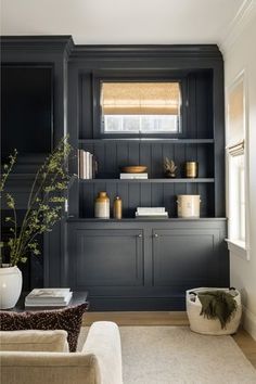 a living room filled with furniture and bookshelves in black painted wood paneling