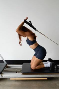 a woman is doing exercises on a treadmill while holding a resistance bar in the air