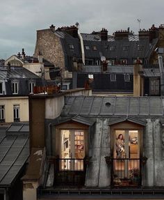 an apartment building with two people standing on the balcony and looking out at the city