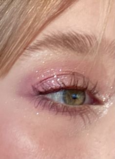 a woman's eye with pink glitter on the lashes and her eyes are closed