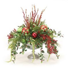 a silver vase filled with red ornaments and greenery on top of a white table