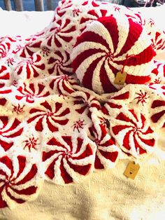 a red and white crocheted blanket sitting on top of a bed