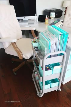 a desk with a chair, computer monitor and many folders on the shelf next to it