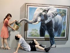 a man and woman standing next to an elephant painting in front of a large wall