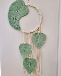 a green and white wall hanging with leaves