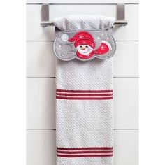 a white towel hanging on the wall next to a metal rack with a red santa hat