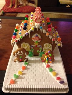 a decorated gingerbread house sitting on top of a white plate with candy and candies