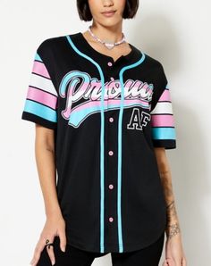 a woman wearing a black baseball jersey with pink, blue and white letters on it