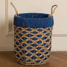 a blue and beige basket sitting on top of a wooden floor