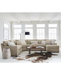 a living room filled with lots of furniture next to two large windows and a cowhide rug on the floor