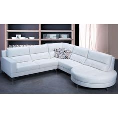 a white leather sectional sofa in front of a bookshelf with shelves behind it