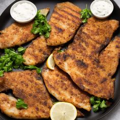 grilled chicken with lemon and parsley garnishes on a black plate