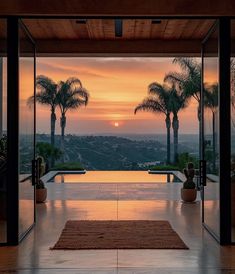 the sun is setting behind palm trees in front of a large glass door that leads to an outdoor swimming pool