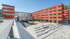 an orange building with stairs leading up to it's second floor and another building in the background