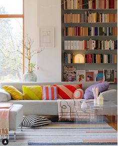 a living room filled with lots of furniture and bookshelves next to a window