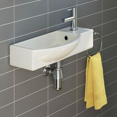 a white sink sitting next to a wall mounted faucet in a tiled bathroom