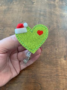 If your looking for a sign to update you badge reel, this is it!  Green glitter heart with a red Santa hat.   Styles to choose from: Alligator Clip.  Clips on (opens up) and rotates 360 degrees with a nylon retractable cord. This is good for pulling and needing it to turn slightly without coming undone.  Belt Clip.  Clips (slides) on clothing with a retractable nylon cord.  It does not rotate.  Premium:  This style can hold 2 ounces (2 Keys), nylon cord extends 36". Tested to last 1 million pull Christmas Badge Reel Ideas, Holiday Badge Reel Ideas, Christmas Badge Reel, Grinch Heart, Cheap Red Badge Reel, Personalized Novelty Badge Reel For Gift, Teacher Badge, Glitter Hearts, Glitter Vinyl