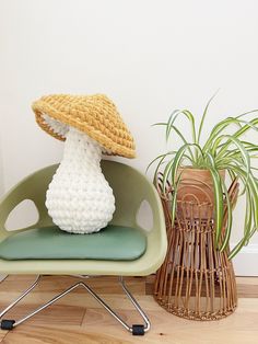 a crocheted mushroom sitting on top of a chair next to a potted plant