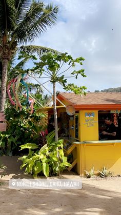 there is a small yellow kiosk on the side of the road with palm trees around it