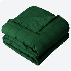 a green comforter is folded up on a white background