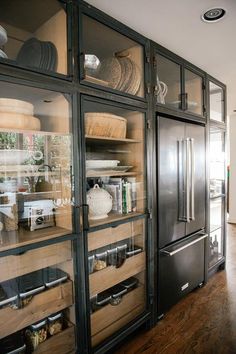 a kitchen with stainless steel appliances and glass doors on the cabinets, along with wooden flooring