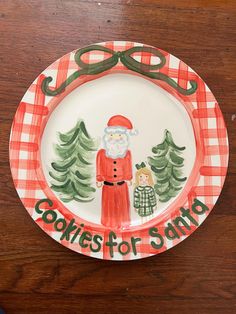 a plate with a santa clause and trees on it that says cookies for santa in green lettering