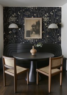 a dining room table with two chairs and a vase on the table in front of it