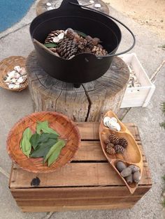 a wooden table topped with bowls filled with pine cones and other items on top of it