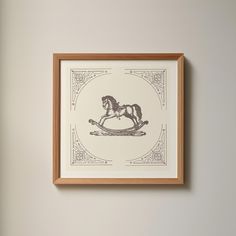 a framed drawing of a rocking horse on the wall above it is an ornate frame