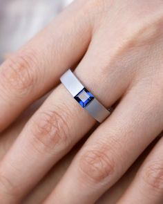 a woman's hand with a ring that has a blue diamond on it and is wearing