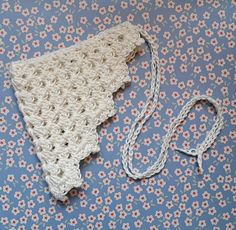 a crocheted piece of cloth laying on top of a blue and white tablecloth